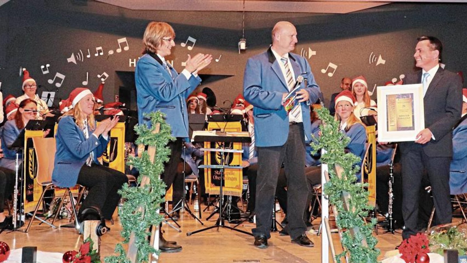 Die stellvertretende Vorsitzende des Musikvereins, Susanne Schray (li), und Uwe Zimmermann (Mitte), Bereichsleiter Kommunikation, ernannten Marco König per Urkunde zum „Meisterdirigenten“. Die stellvertretende Vorsitzende des Musikvereins, Susanne Schray (li), und Uwe Zimmermann (Mitte), Bereichsleiter Kommunikation, ernannten Marco König per Urkunde zum „Meisterdirigenten“.