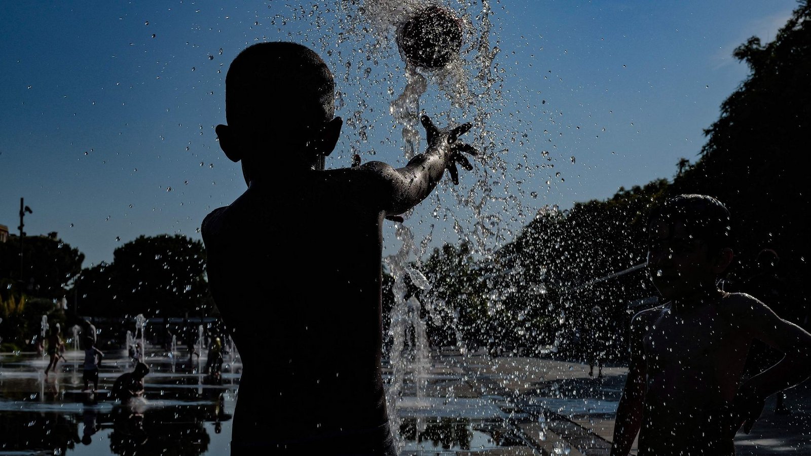 Kinder spielen mit einem Ball in einem Springbrunnen in Nizza.Foto: Valery Hache/AFP/dpa Kinder spielen mit einem Ball in einem Springbrunnen in Nizza.Foto: Valery Hache/AFP/dpa