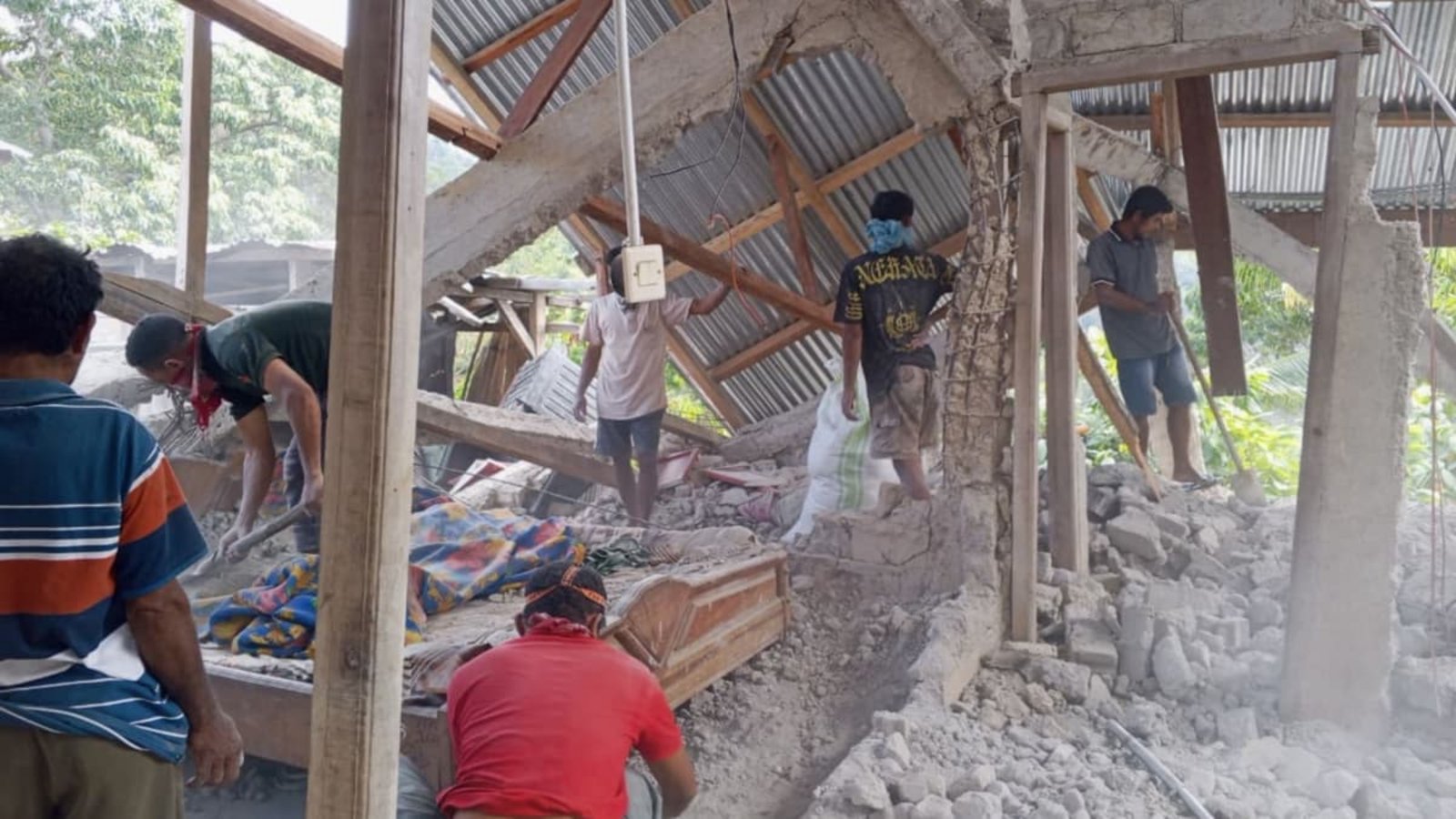Menschen räumen die Trümmer eines durch ein Erdbeben beschädigten Hauses in Ost-Manggarai in der Provinz Ost-Nusa Tenggara weg.Kurniawan/AP/dpa