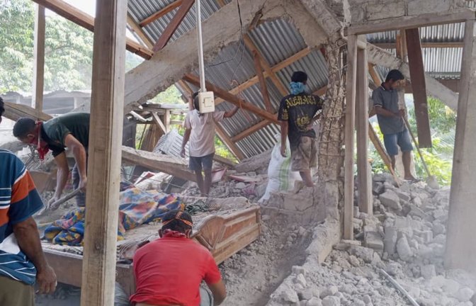 Menschen räumen die Trümmer eines durch ein Erdbeben beschädigten Hauses in Ost-Manggarai in der Provinz Ost-Nusa Tenggara weg.<span class='image-autor'>Kurniawan/AP/dpa</span>
