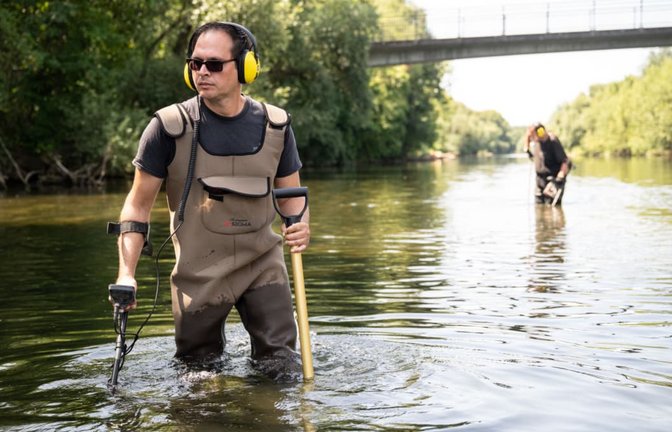 Der Ringsucher Andreas Rottler durchkämmt den Neckar mit dem Metalldetektor, im Hintergrund Peter Bäumler. An der Brücke ging das Stocherkahnrennen los, irgendwo dort könnte der Ehering von Jonas Hörrmann liegen.<span class='image-autor'>Carolin Albers</span>