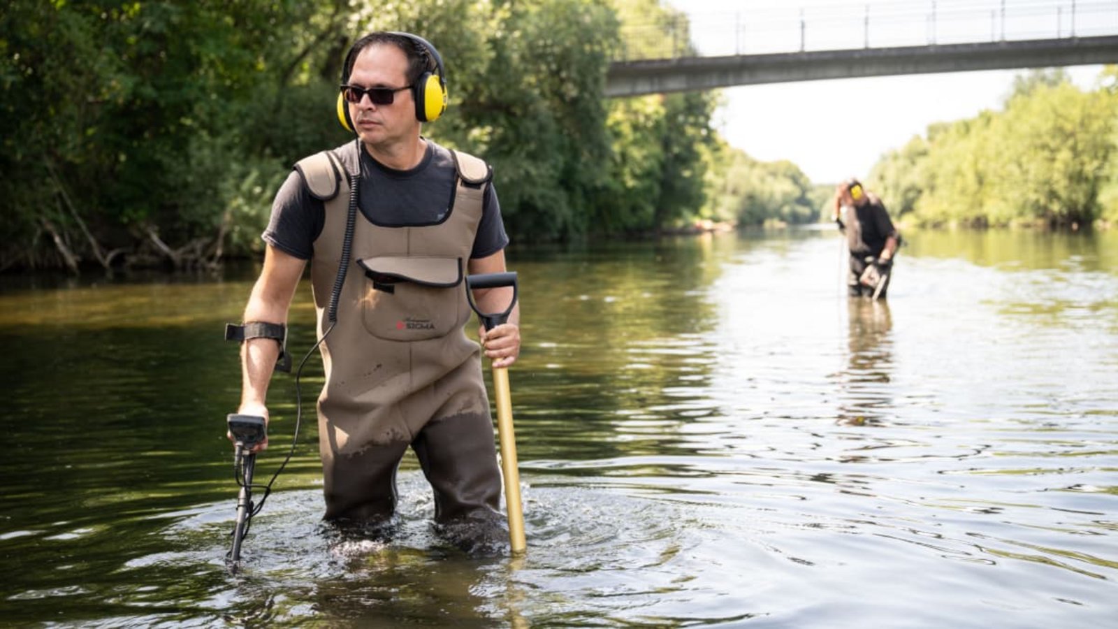 Der Ringsucher Andreas Rottler durchkämmt den Neckar mit dem Metalldetektor, im Hintergrund Peter Bäumler. An der Brücke ging das Stocherkahnrennen los, irgendwo dort könnte der Ehering von Jonas Hörrmann liegen.Carolin Albers