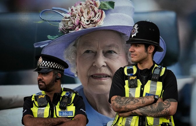 Polizisten stehen in London vor einem Bild von Königin Elizabeth II. - die Monarchin ruht vier Tage lang in der Westminster Hall, bevor sie am Montag beigesetzt wird.<span class='image-autor'>Foto: Vadim Ghirda/AP/dpa</span>