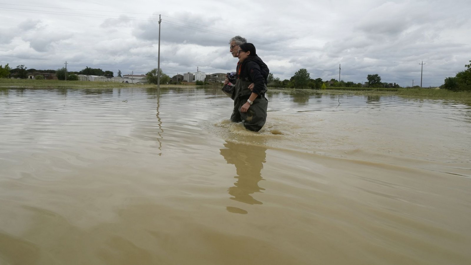 Ein Paar überquert eine überflutete Straße bei der Stadt Lugo. Nach den Unwettern und Überschwemmungen in Italien ist die Anzahl der Opfer weiter gestiegen.Foto: Luca Bruno/AP/dpa Ein Paar überquert eine überflutete Straße bei der Stadt Lugo. Nach den Unwettern und Überschwemmungen in Italien ist die Anzahl der Opfer weiter gestiegen.Foto: Luca Bruno/AP/dpa