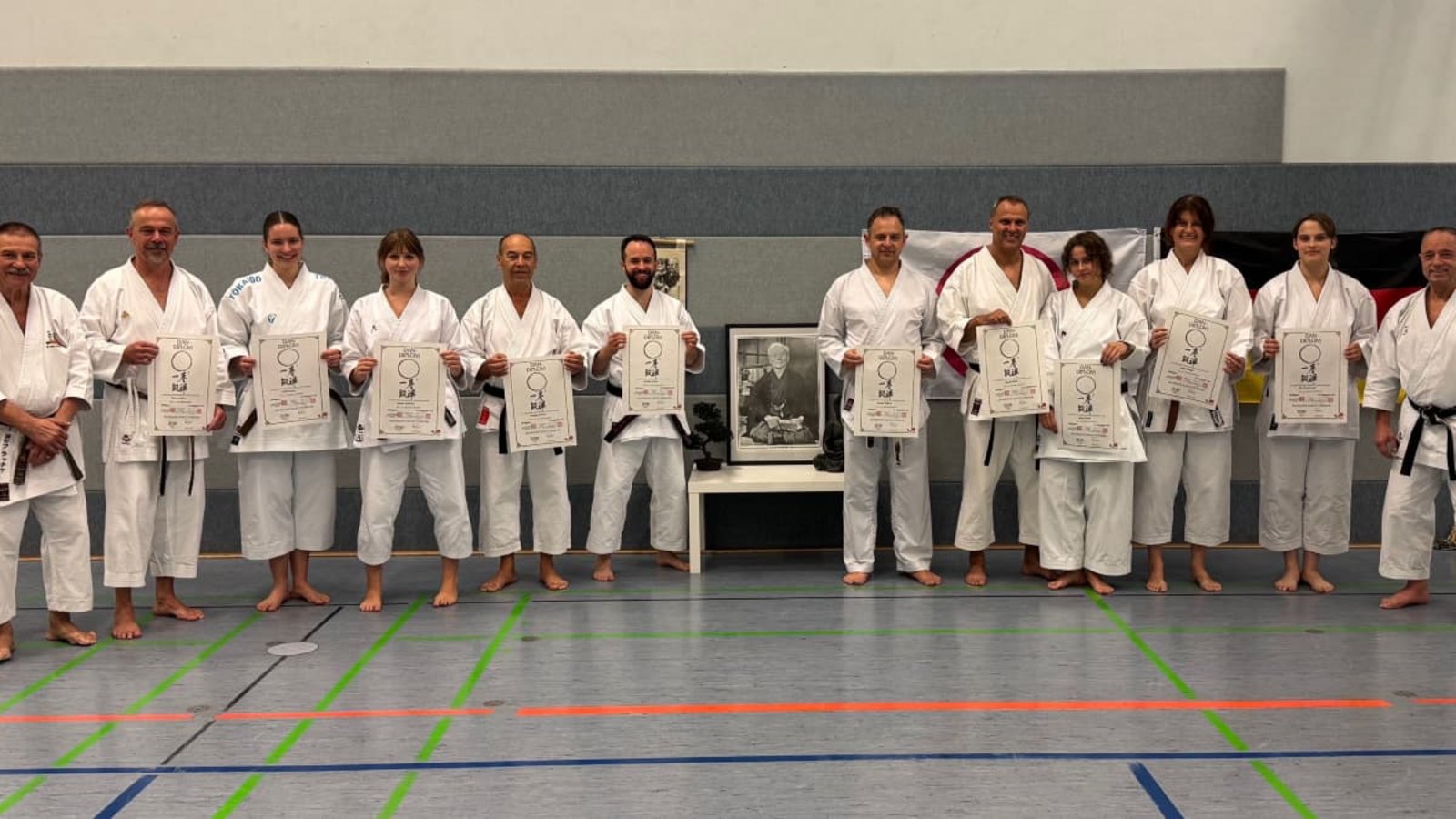 Zehn neue Dan-Diplome (von links nach rechts): Prüfer Lothar Ratschke, Thomas Kühn, Liliane Lanz, Jessica Schröder, Georg Dimas, Patrick Raichle, Martin Geldner, Harald und Alissa Pfaffl, Katja Philipp, Ria Markwardt und Prüfer Andreas StavrakakisSVB