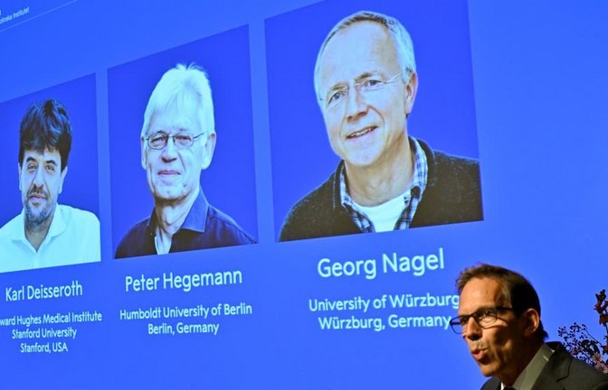 Die Bilder von Karl Deisseroth, Peter Hegemann und Georg Nagel sind auf einem Monitor zu sehen, als ihnen der Nobelpreis für Physiologie oder Medizin 2026 verliehen wird. Dies wird im Rahmen einer Pressekonferenz im Nobel-Forum am Karolinska-Institut in Stockholm, Schweden, bekannt gegeben.<span class='image-autor'>Pontus Lundahl/TT News Agency/AP/dpa</span>