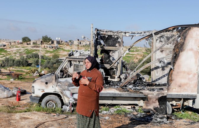 Eine Bewohnerin steht neben einem ausgebrannten Fahrzeug im Dorf Susya bei Hebron im besetzten Westjordanland. Israelische Siedler sollen Ende Februar dort Zelte und Autos angezündet haben.<span class='image-autor'>Foto: IMAGO/Middle East Images/IMAGO/Mosab Shawer</span>