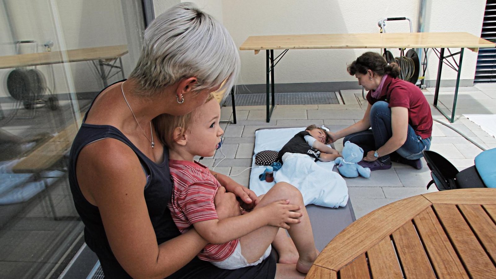 Katharina Ullrich und ihre Söhne Evin und Joel verbringen einen sonnigen Vormittag im Hof der Familienherberge Lebensweg in Schützingen. Eine Pflegerin ist hier immer an Joels Seite.   Fotos: Rieger