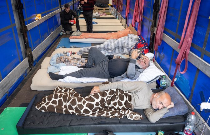 Trucker aus Georgien liegen auf einem Matratzenlager auf der Ladefläche eines Lkw. Sie sind in einen Hungerstreik getreten.<span class='image-autor'>Foto: Boris Roessler/dpa</span>