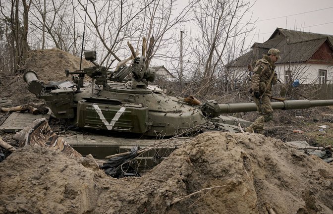 Ein ukrainischer Soldat geht an einem verlassenen Panzer der russischen Armee in der Stadt Andrijiwka  vorbei.<span class='image-autor'>Foto: AP/dpa/Vadim Ghirda</span>