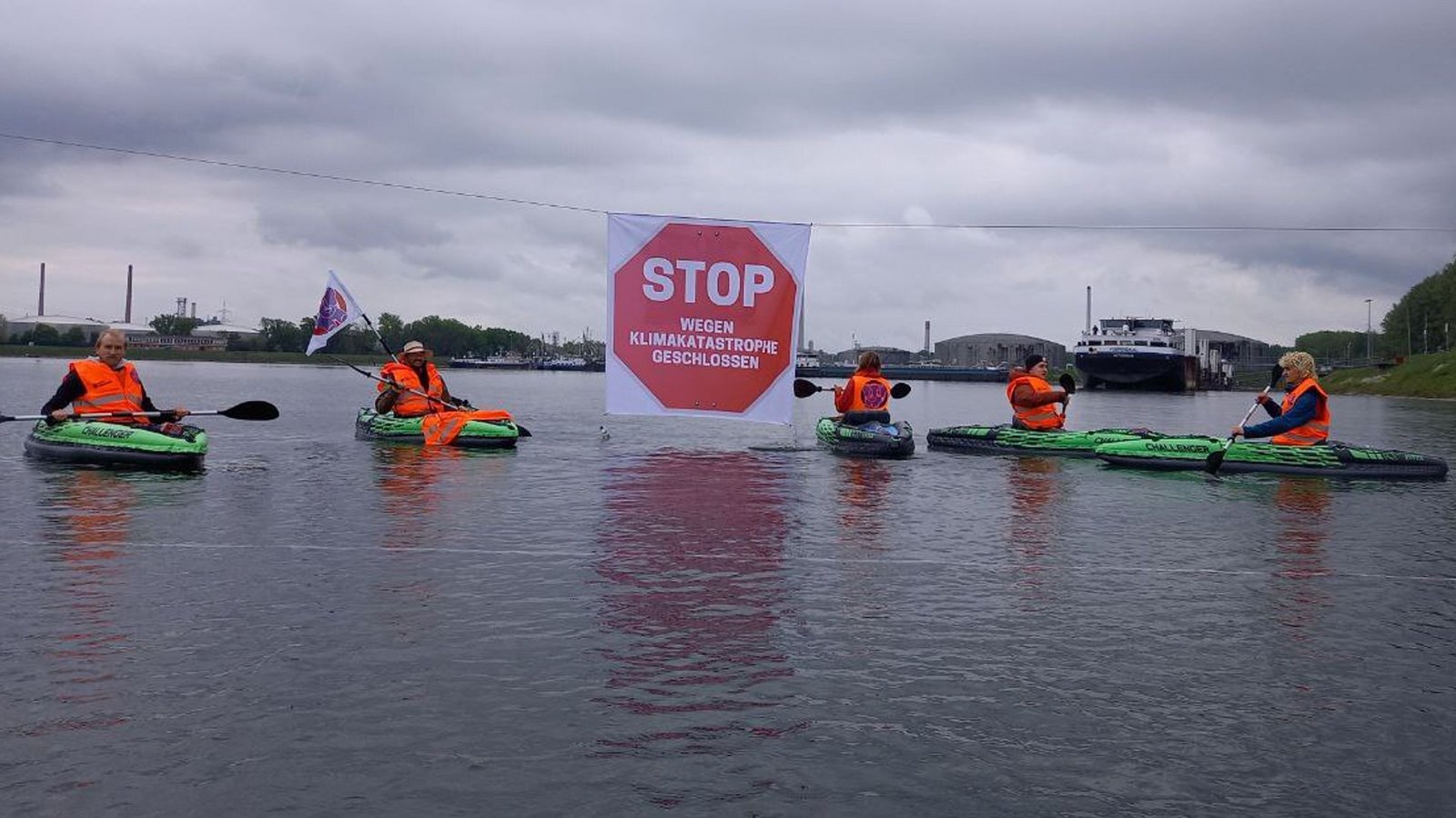 Klimaaktivisten der „Letzten Generation“ in Warnwesten blockieren mit Kajaks die Kanalzufahrt zum Ölhafen.Foto: dpa