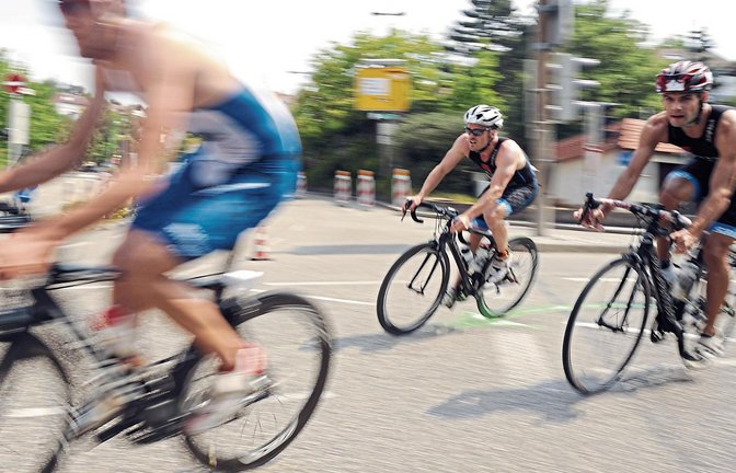 Mit ordentlich Tempo schießen die Triathleten auf dem Rennrad um eine Ecke. Foto: Fotomoment