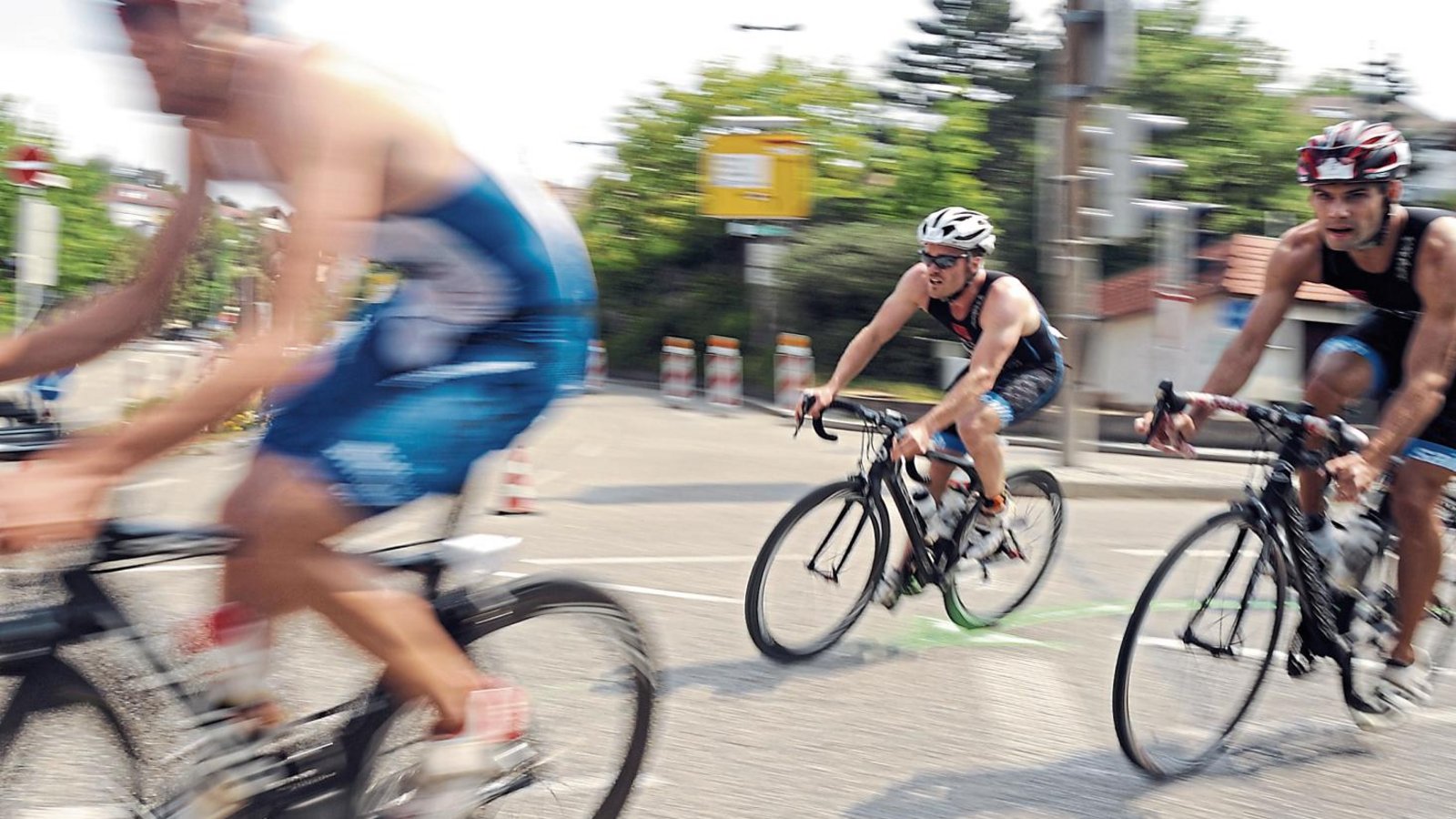 Mit ordentlich Tempo schießen die Triathleten auf dem Rennrad um eine Ecke. Foto: Fotomoment