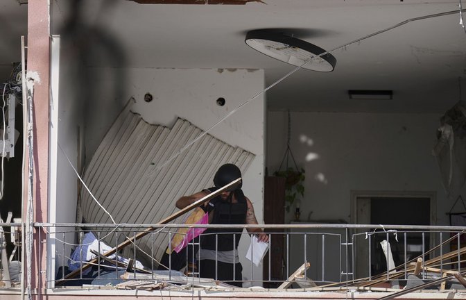 Ein Mann holt in der israelischen Hafenstadt Habseligkeiten aus einer Wohnung, die nach dem Einschlag einer iranischen Rakete beschädigt wurde.<span class='image-autor'>Foto: Ariel Schalit/AP/dpa</span>