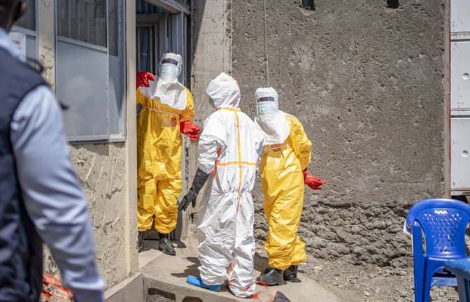 Gesundheitsmitarbeiter in Ganzkörper-Schutzanzügen stehen vor einem Klinik-Gebäude in der Stadt Goma.<span class='image-autor'>Imago/Xinhua</span>