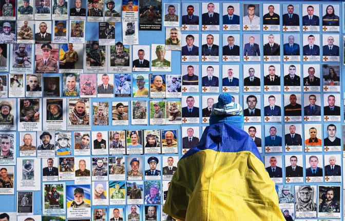 Eine Frau steht in Kiew vor einer Gedenktafel mit Fotos gefallenere Soldaten.<span class='image-autor'>Foto: dpa/Andrew Kravchenko</span>