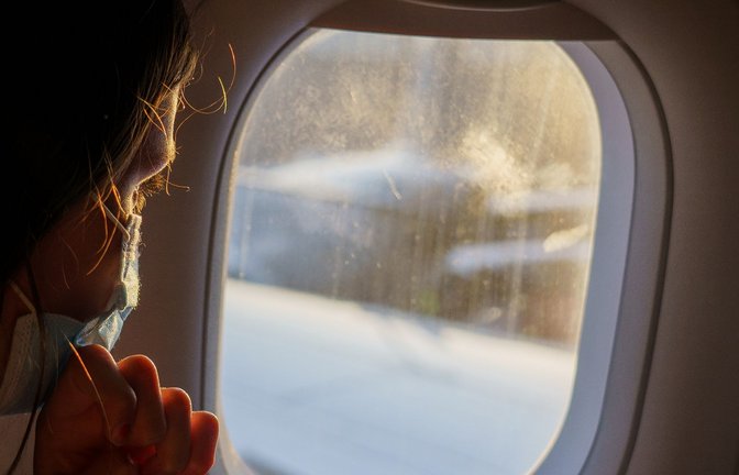 Ein weiblicher Fluggast mit Maske schaut vor dem Start aus dem Fenster. Auf Flügen von und nach Deutschland muss weiter Maske getragen werden.<span class='image-autor'>Foto: Andreas Arnold/dpa</span>