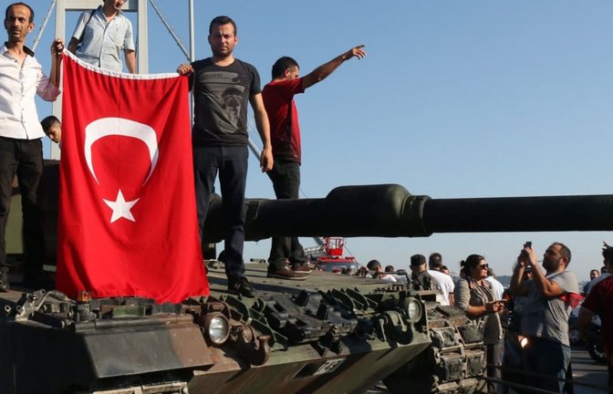 Türkische Polizisten und Anhänger von Präsident Erdogan stehen nach dem gescheiterten Putsch mit einer türkischen Flagge auf einem Panzer auf der Bosporusbrücke. Bei dem Putschversuch vom 15. Juli 2016 waren mehr als 200 Menschen getötet und mehr als 2000 verletzt worden (Archivfoto).<span class='image-autor'>Str/EPA/dpa</span>