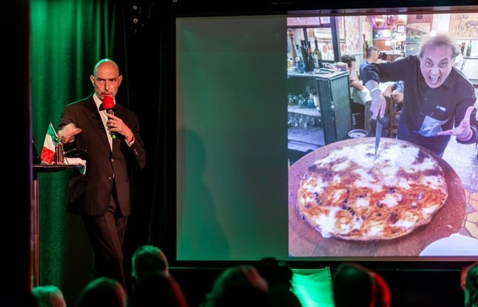Eric Pfeil liest im Stuttgarter Kulturzentrum Merlin aus seinem Buch „Hotel Celentano“ und zeigt dabei ein Bild von riesigen Pizzen. Foto: Lichtgut/Christoph Schmidt<span class='image-autor'>Christoph Schmidt</span>