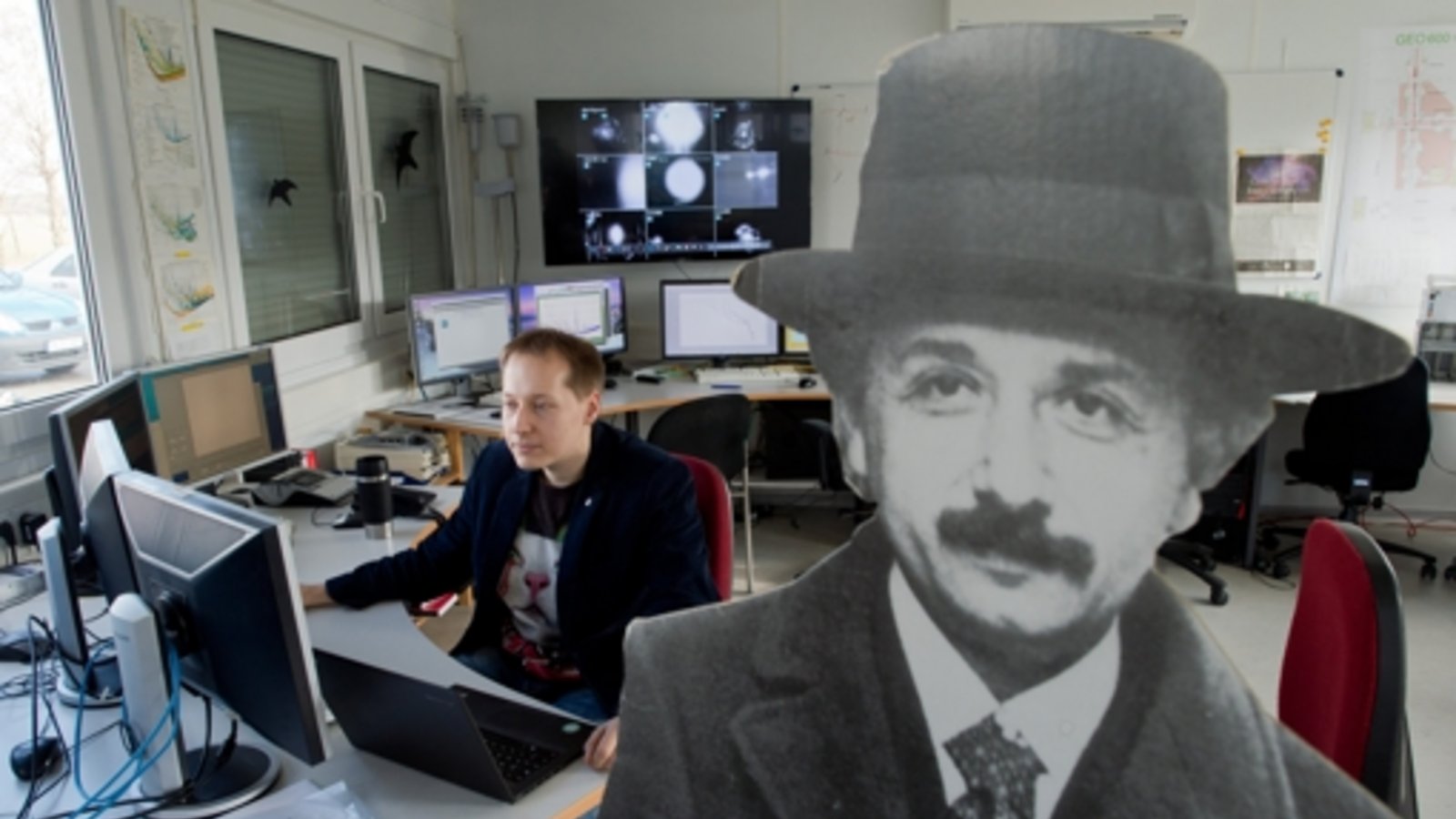 Einstein ist überall: Ein Wissenschaftler sitzt in einem Kontrollraum des Gravitationswellendetektors GEO600 neben einem Pappaufsteller, der Albert Einstein, den deutschen Physik-Nobelpreisträger von 1922, darstellt.Foto: dpa Einstein ist überall: Ein Wissenschaftler sitzt in einem Kontrollraum des Gravitationswellendetektors GEO600 neben einem Pappaufsteller, der Albert Einstein, den deutschen Physik-Nobelpreisträger von 1922, darstellt.Foto: dpa