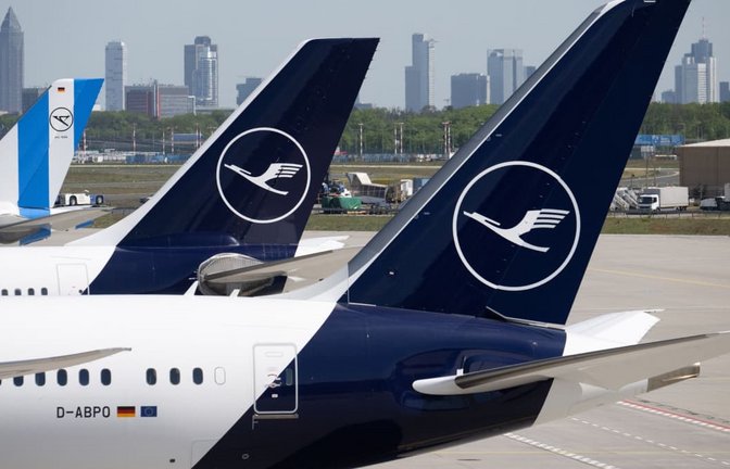 Passagiermaschinen der Lufthansa und der Condor stehen am Flughafen Frankfurt, während im Hintergrund die Bankentürme von Frankfurt zu sehen sind. (Symbolbild)<span class='image-autor'>Boris Roessler/dpa</span>