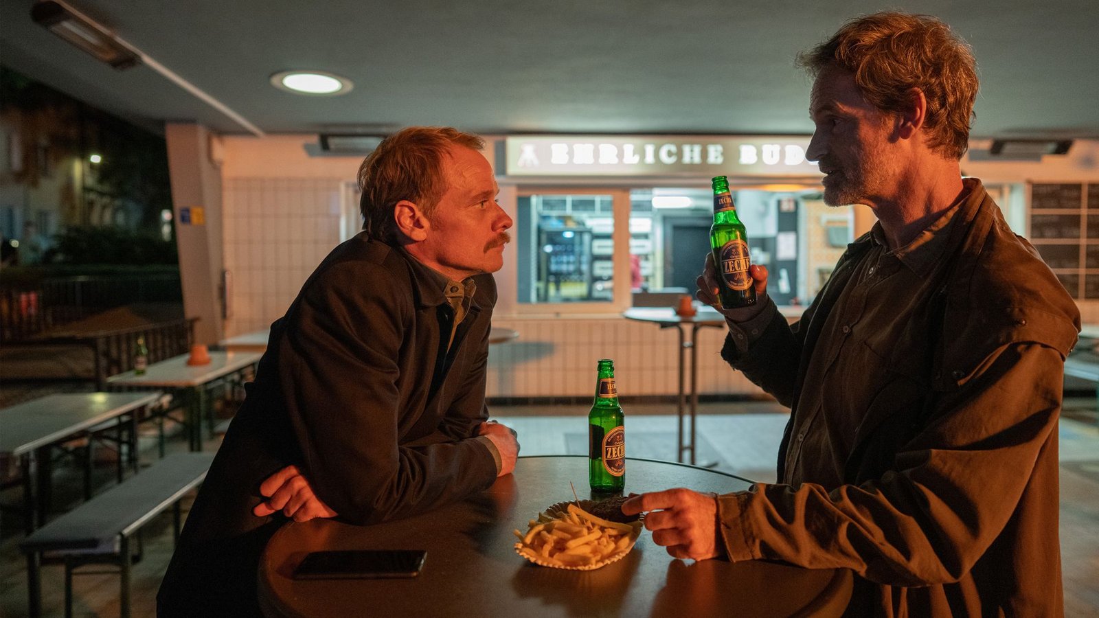 Daniel Kossik (Stefan Konarske, l) und Peter Faber (Jörg Hartmann, r), unterhalten sich bei einer Currywurst über die Ermittlungen zum Mord an Haller in gewohnt feindseliger Manier.Foto: WDR/Thomas Kost