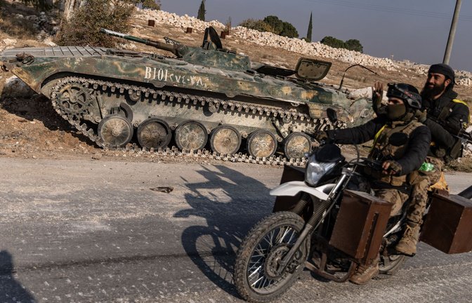 Syrische Oppositionskämpfer fahren an einem erbeuteten Panzer des syrischen Regimes in Kafr Naya in der Provinz Aleppo vorbei.<span class='image-autor'>Foto: dpa/Anas Alkharboutli</span>