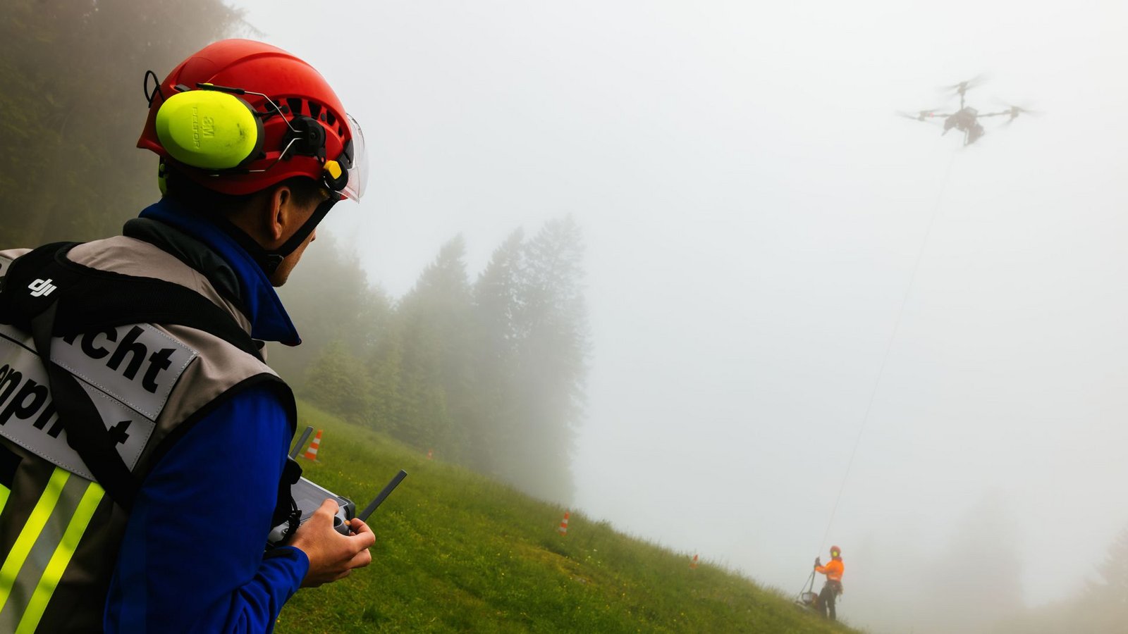 Ein Drohnenpilot der Bergwacht sieht zu, wie ein Flughelfer der Bergwacht eine Übungslast von der Seilwinde einer Lastendrohne abhängt.Foto: Philipp von Ditfurth/dpa Ein Drohnenpilot der Bergwacht sieht zu, wie ein Flughelfer der Bergwacht eine Übungslast von der Seilwinde einer Lastendrohne abhängt.Foto: Philipp von Ditfurth/dpa