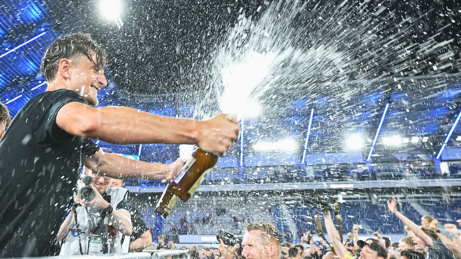 Arena. Spieler von SC Paderborn 07 spritzt mit einer Sektflasche im Stadion.Foto: Swen Pförtner/dpa