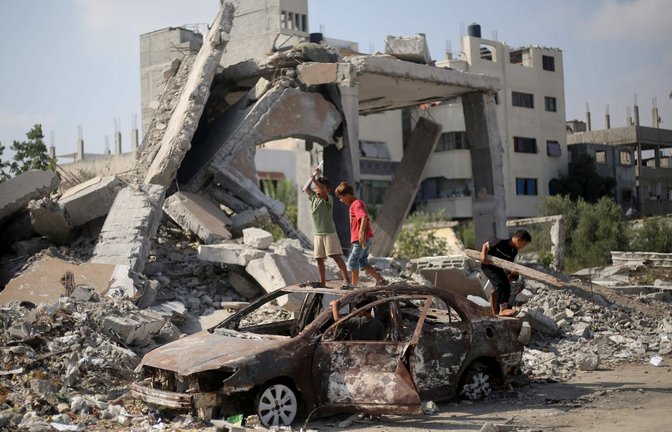 Palästinensische Kinder spielen am 23. Juli nach israelischem Beschuss auf den Trümmern eines Autos im Flüchtlingslager al-Bureij im zentralen Gazastreifen (Archivfoto).<span class='image-autor'>Foto: AFP/EYAD BABA</span>