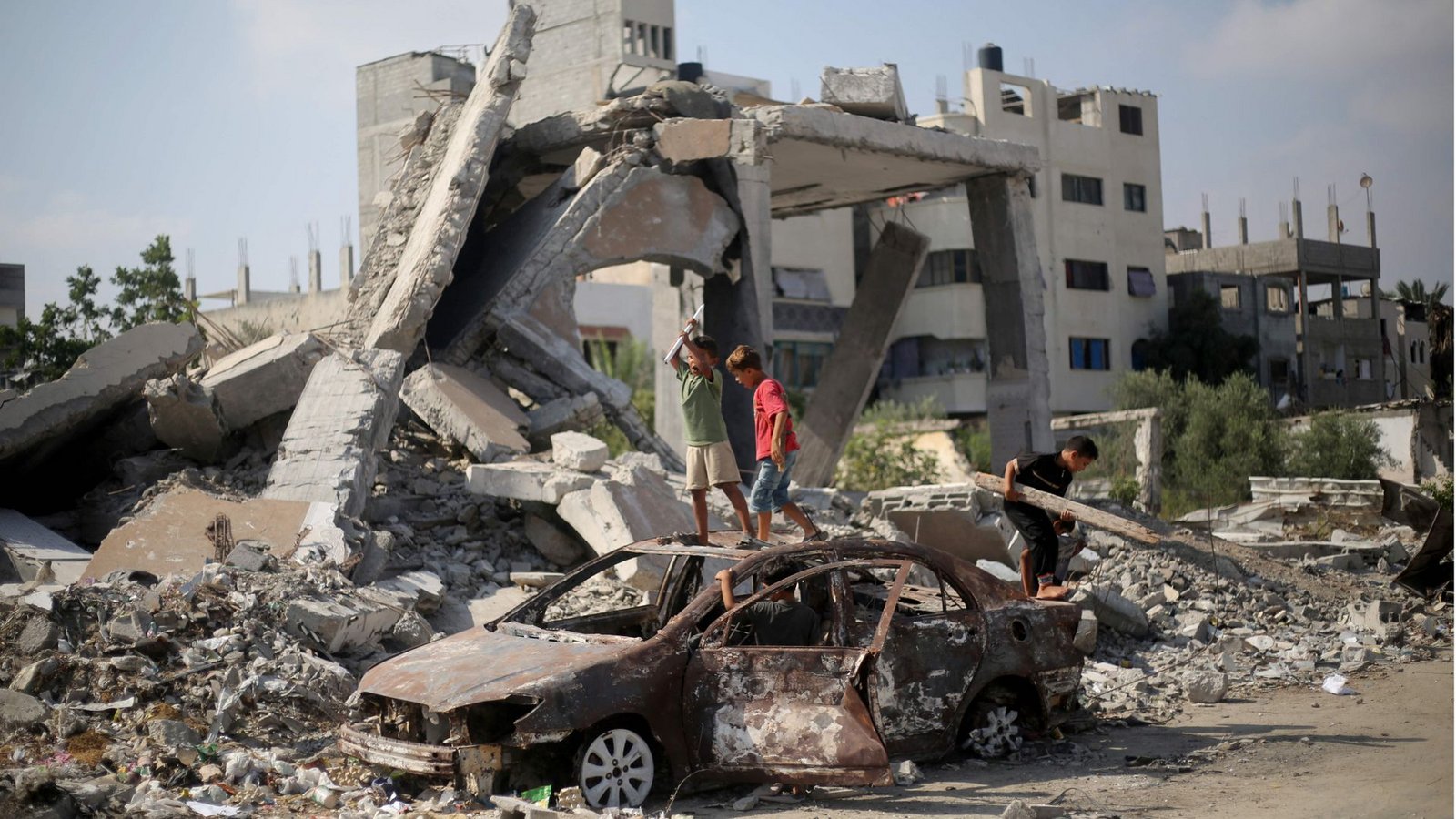 Palästinensische Kinder spielen am 23. Juli nach israelischem Beschuss auf den Trümmern eines Autos im Flüchtlingslager al-Bureij im zentralen Gazastreifen (Archivfoto).Foto: AFP/EYAD BABA