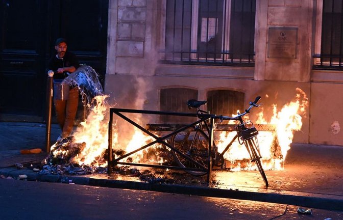 Ein Mann versucht in Paris, während der Zusammenstöße zwischen Demonstranten und Polizeibeamten ein Feuer zu löschen.<span class='image-autor'>Foto: Emma Da Silva/AP/dpa</span>