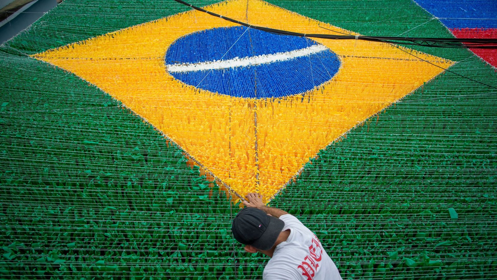 Eine Person gibt der hängenden Dekoration zur Feier der Fußballweltmeisterschaft 2026 auf der Rua 03 im Viertel Alvorada in Manaus, der Hauptstadt des brasilianischen Bundesstaates Amazonas, den letzten Schliff.Foto: Suamy Beydoun/dpa Eine Person gibt der hängenden Dekoration zur Feier der Fußballweltmeisterschaft 2026 auf der Rua 03 im Viertel Alvorada in Manaus, der Hauptstadt des brasilianischen Bundesstaates Amazonas, den letzten Schliff.Foto: Suamy Beydoun/dpa