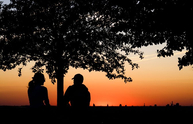 Ein Paar genießt kurz nach Sonnenuntergang auf dem Kronsberg in Hannover das sommerliche Wetter.<span class='image-autor'>Foto: Julian Stratenschulte/dpa</span>