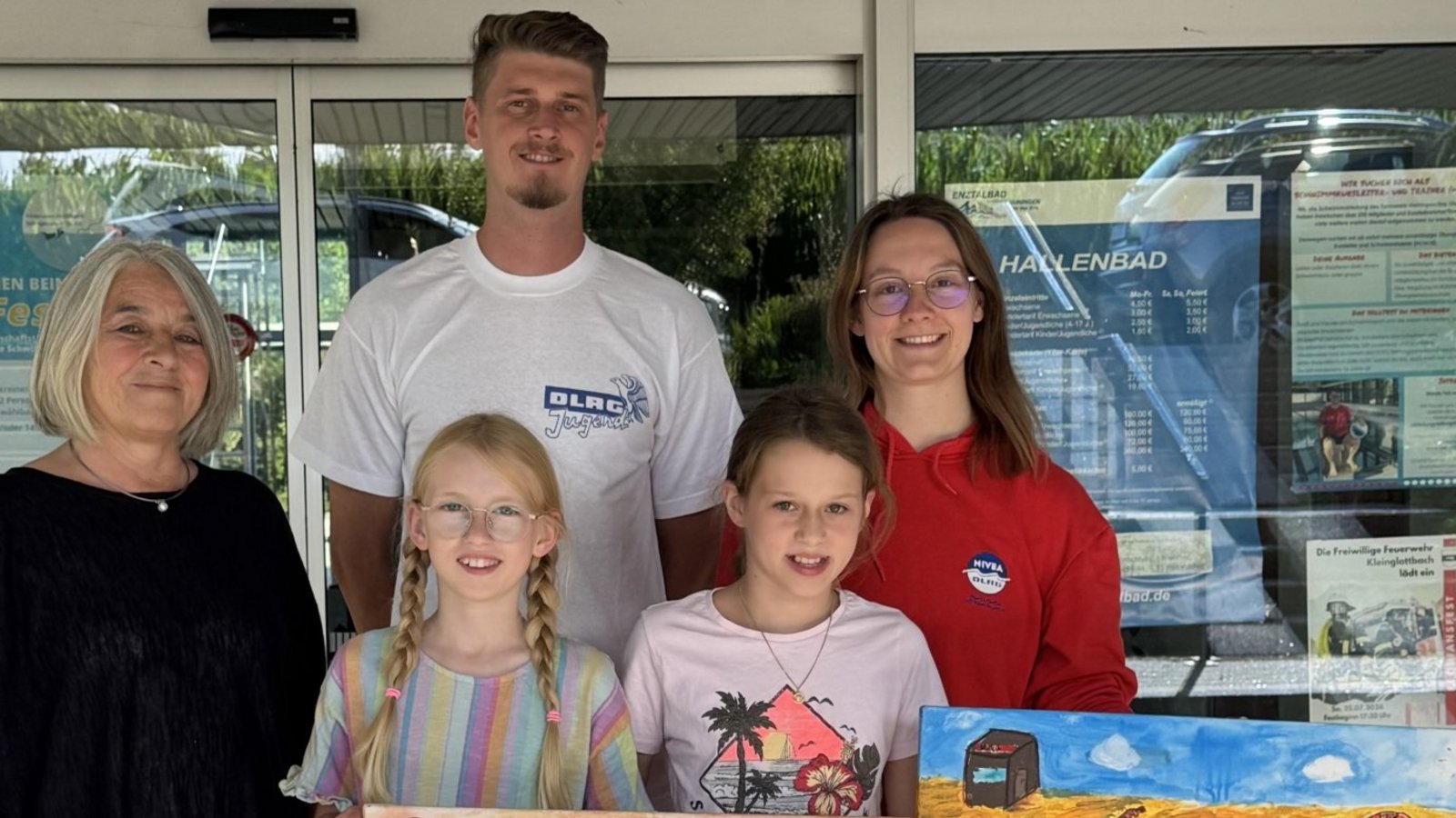 Stolz überreichen zwei Grundschülerinnen die Bilder, die nun das Vereinsheim der DLRG verschönern werden. Foto: p Stolz überreichen zwei Grundschülerinnen die Bilder, die nun das Vereinsheim der DLRG verschönern werden. Foto: p