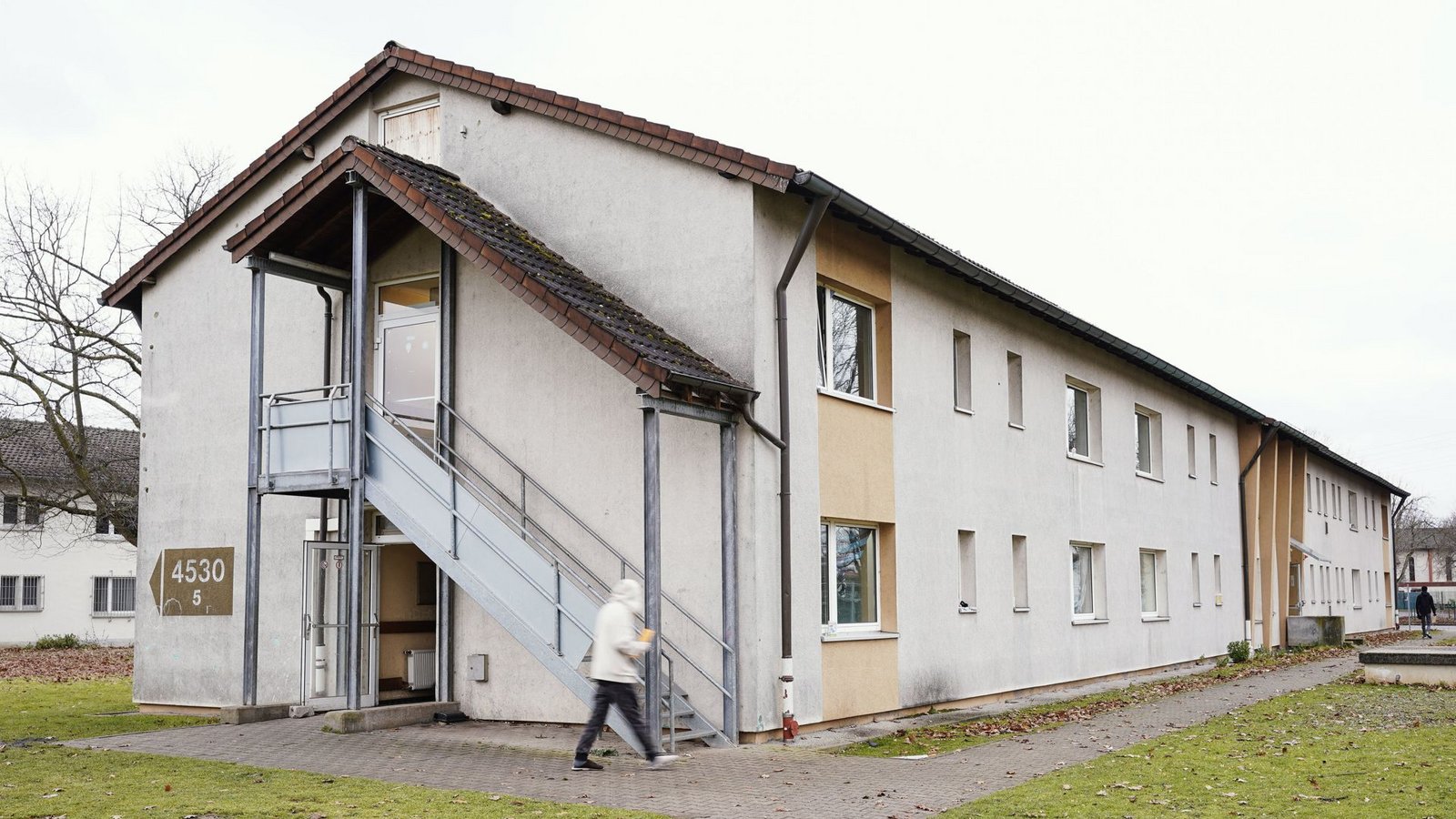 Ein Bewohner geht am 8.12.2021 im Ankunftszentrum für Flüchtlinge auf dem Gelände der ehemaligen US-Militärfläche Patrick-Henry-Village in Heidelberg an einem Wohnhaus vorbei.Foto: dpa/Uwe Anspach Ein Bewohner geht am 8.12.2021 im Ankunftszentrum für Flüchtlinge auf dem Gelände der ehemaligen US-Militärfläche Patrick-Henry-Village in Heidelberg an einem Wohnhaus vorbei.Foto: dpa/Uwe Anspach