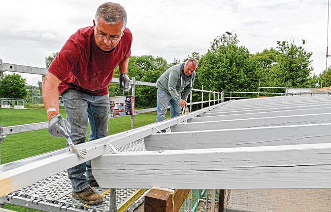 Manfred Dupper (links) und Reiner Schneider legen beim Streichen der neuen Dachbalken selbst Hand an. Einige Arbeiten mussten allerdings aus versicherungstechnischen Gründen von Fachfirmen ausgeführt werden. Foto: Leitner