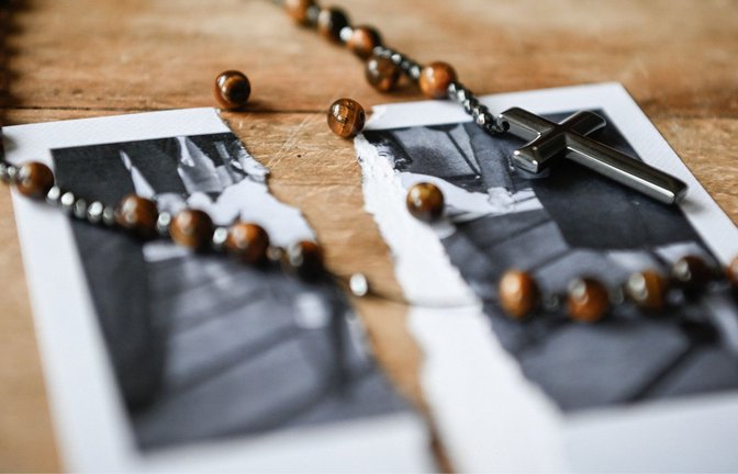 Ein kaputter Rosenkranz liegt auf einem zerrissenen Bild von einem kleinen Mädchen auf einem Tisch, am 27. Januar 2022. Das Bistum äußert sich zum Missbrauchsgutachten.<span class='image-autor'>Foto: KNA Katholische Nachrichten-Agen/Julia Steinbrecht</span>