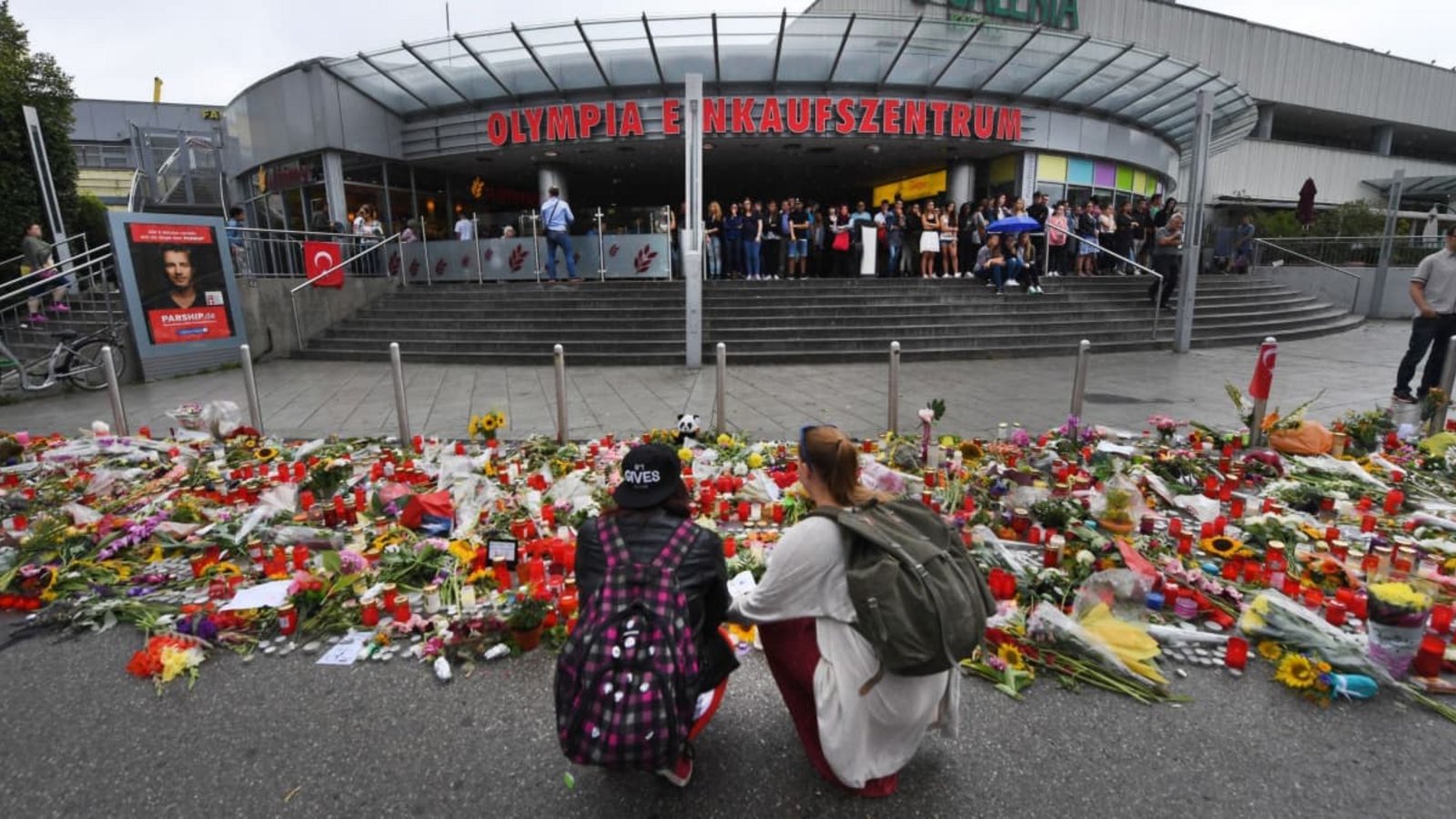 Blumen und Kerzen liegen vor dem Haupteingang des Olympia-Einkaufszentrums (OEZ). Drei Tage zuvor hatte dort ein 18-Jähriger neun Menschen erschossen und sich danach selbst getötet.Peter Kneffel/dpa Blumen und Kerzen liegen vor dem Haupteingang des Olympia-Einkaufszentrums (OEZ). Drei Tage zuvor hatte dort ein 18-Jähriger neun Menschen erschossen und sich danach selbst getötet.Peter Kneffel/dpa