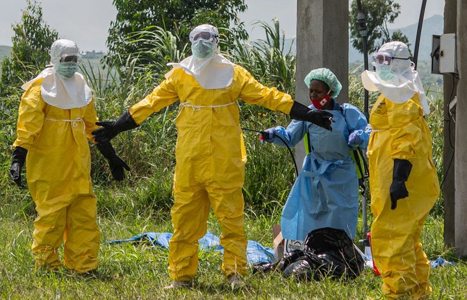 Mitarbeiter des Roten Kreuzes in Schutzkleidung desinfizieren sich.<span class='image-autor'>Foto: Moses Sawasawa/AP/dpa</span>