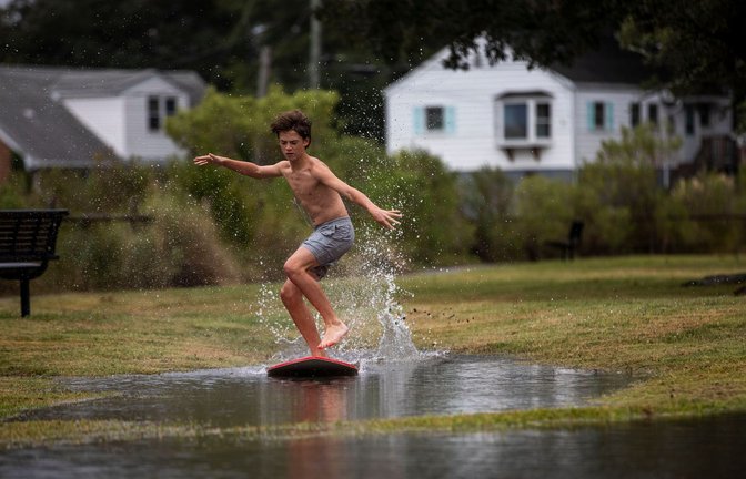 Ein Junge gleitet in Norfolk im US-Bundesstaat Virginia über das hohe Wasser des Lafayette River, während sich der Tropensturm "Ophelia" nähert.<span class='image-autor'>Foto: Kendall Warner/The Virginian-Pilot/AP/dpa</span>