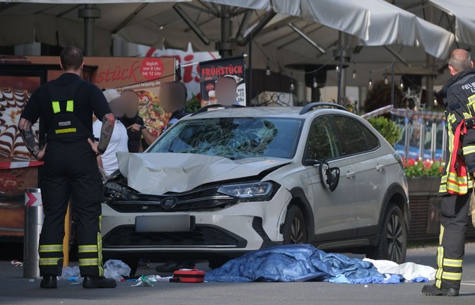 Einsatzkräfte und weitere Personen stehen um ein beschädigtes Auto. In Leipzig ist ein Auto in mehrere Menschen gefahren.<span class='image-autor'>Foto: Sebastian Willnow/dpa/Sebastian Willnow</span>
