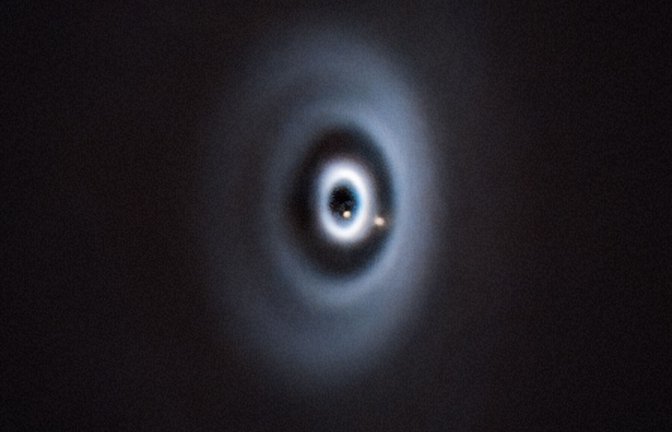 Etwa so könnte es bei der Entstehung der Erde in unserem Sonnensystem ausgesehen haben. Geburt von zwei Planeten (beige Punkte) in einer protoplanetaren Scheibe um den jungen Stern WISPIT 2.<span class='image-autor'>Foto: ESO CC 4.0/C. Lawlor, R. F. van Capel</span>