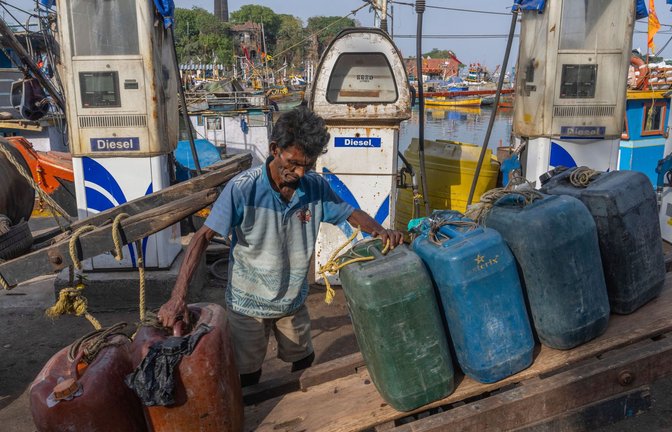 Ein indischer Arbeiter ordnet leere Treibstoffkanister auf seinem Handkarren im Hafen von Mumbai.<span class='image-autor'>Foto: Rafiq Maqbool/AP/dpa</span>