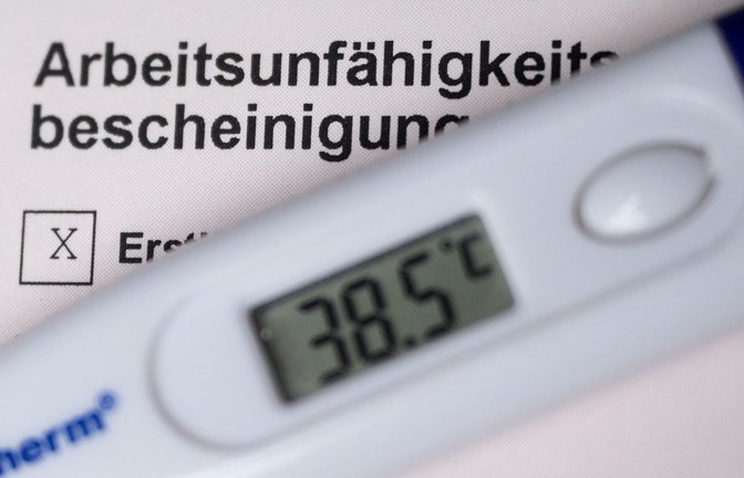 Ein Fieberthermometer liegt auf einer Arbeitsunfähigkeitsbescheinigung (gestellte Szene).<span class='image-autor'>Foto: dpa/Marijan Murat</span>