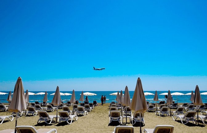 Sonne am Strand von Larnaka in Zypern. Im Hintergrund ein Flugzeug im Anflug auf den Flughafen.<span class='image-autor'>Foto: dpa/Petros Karadjias</span>