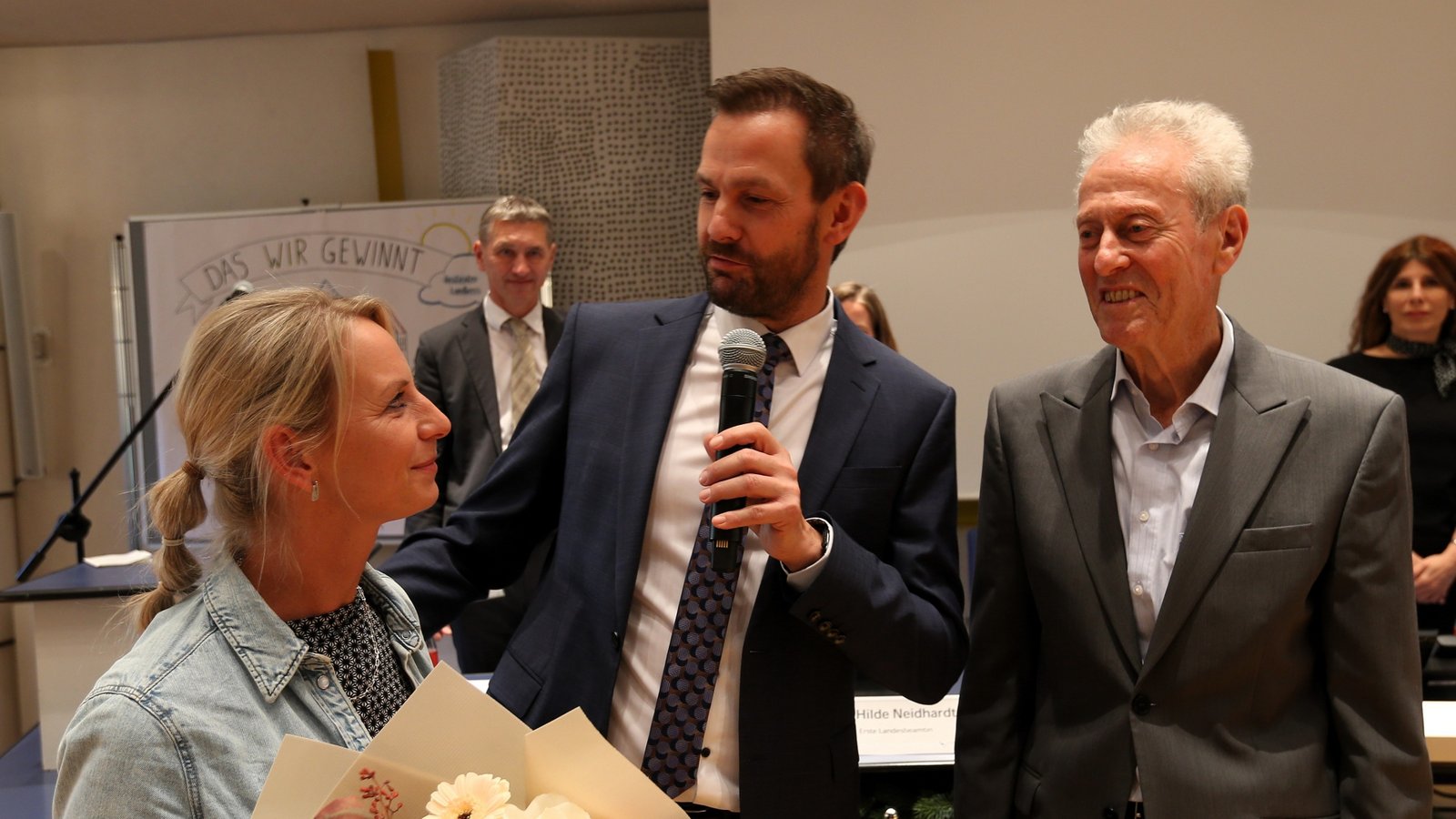 Der alte und neue Enzkreis-Landrat Bastian Rosenau (Mitte) mit Ehefrau Natalie und Sitzungsleiter Jürgen Kurz nimmt die Wahl an und bedankt sich bei der Familie für die Unterstützung. Foto: Küppers