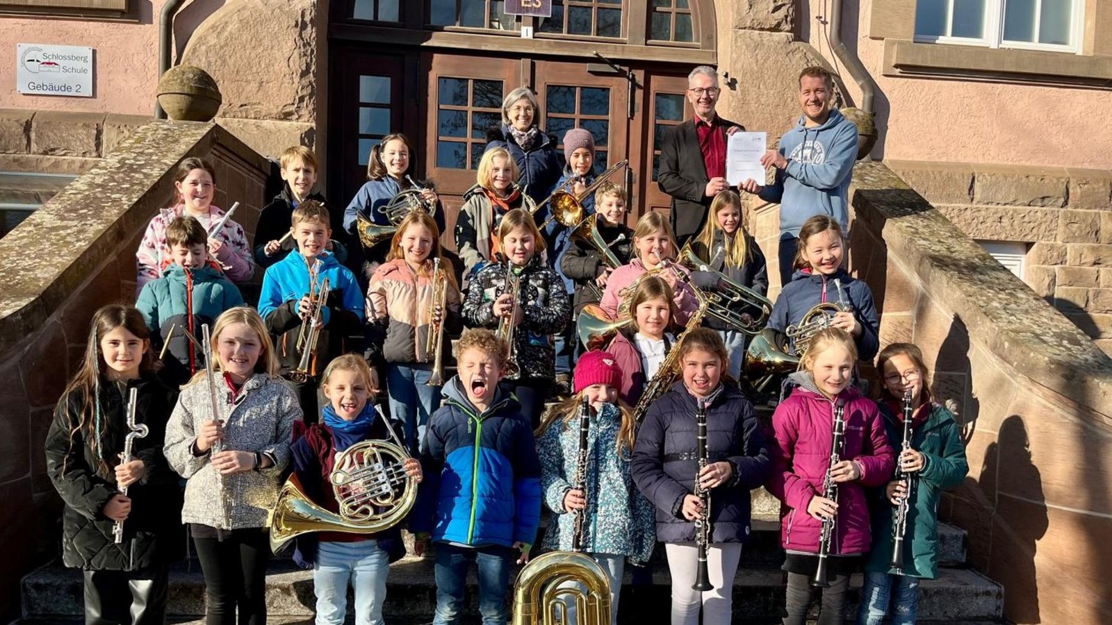 Einen musikalischen Tusch für die Zusammenarbeit gibts von der Bläserklasse. Hinten präsentieren Rektor Jürgen Joos (rechts) und Gerd Wagner vom MVV den erneuerten Vertrag. Foto: p Einen musikalischen Tusch für die Zusammenarbeit gibts von der Bläserklasse. Hinten präsentieren Rektor Jürgen Joos (rechts) und Gerd Wagner vom MVV den erneuerten Vertrag. Foto: p