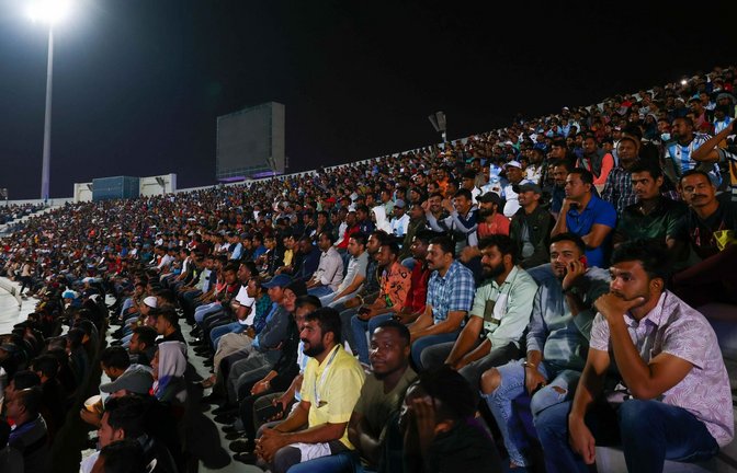 Arbeiter, überwiegend aus Indien, Bangladesch, Nepal und anderen ärmeren Ländern Asiens, verfolgen ein WM-Spiel auf einer Großbildlwand.<span class='image-autor'>Foto: Christian Charisius/dpa</span>
