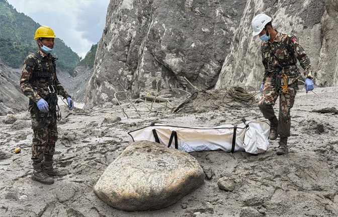 Soldaten der nepalesischen Armee tragen die Leiche eines Arbeiters, die an der Baustelle eines Wasserkraftprojekts in Upper Trishuli, Nepal, geborgen wurde.<span class='image-autor'>Kaslai Dine/AP/dpa</span>